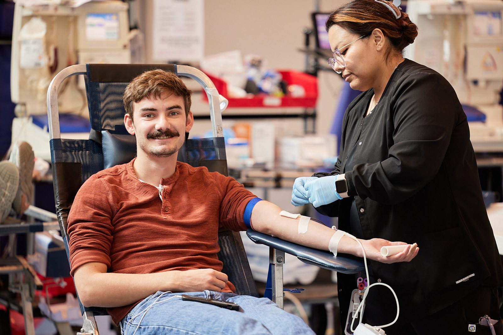 Phlebotomist Smiling next to donor in a chair