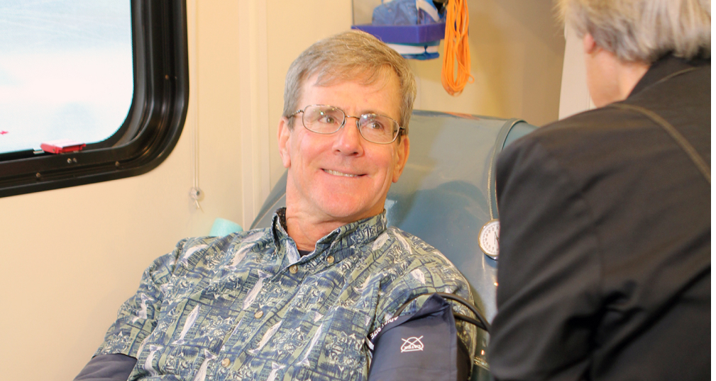 Man in chair donating blood, smiling